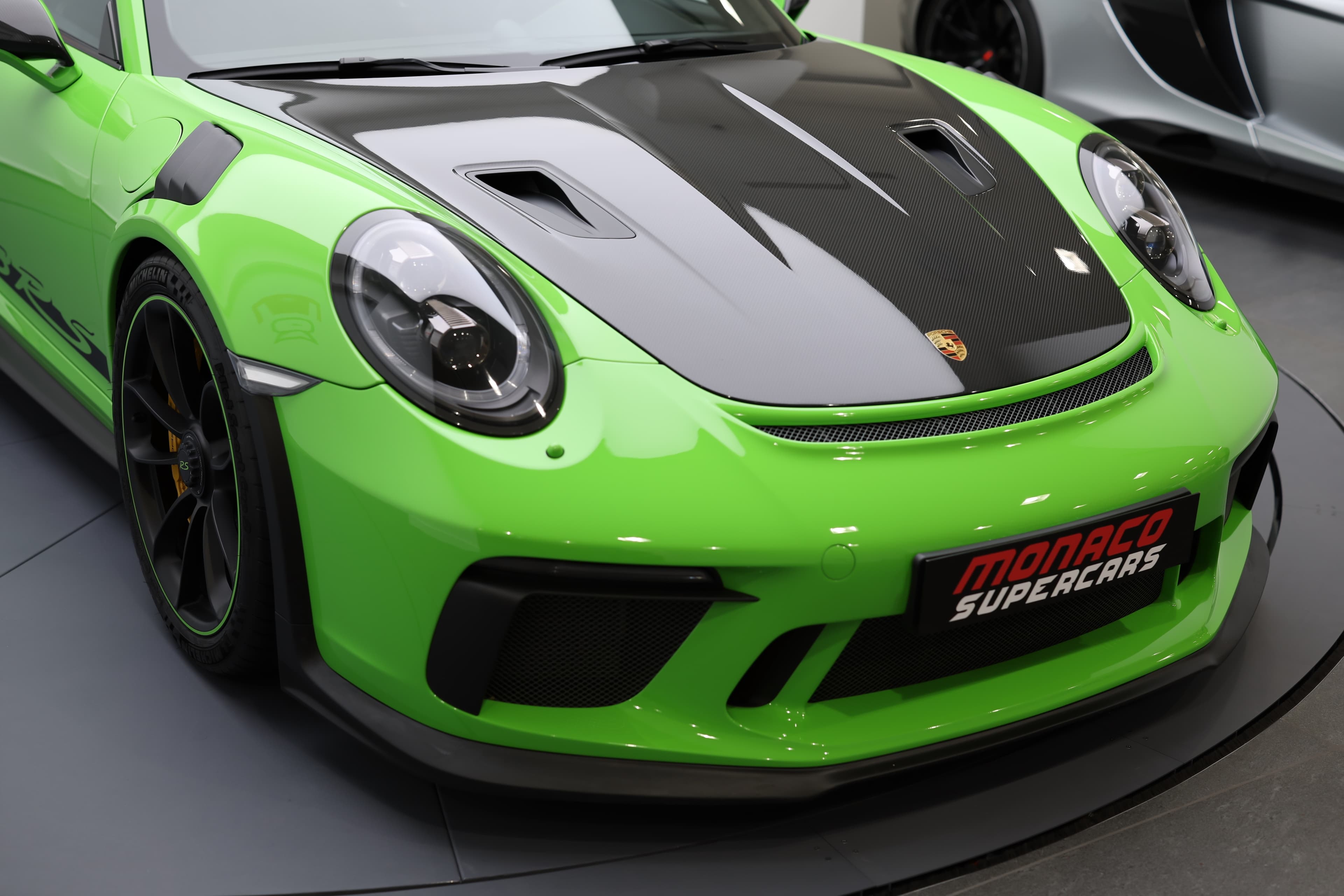 Porsche 911 GT3 RS 991 verte, vue avant trois-quarts, mettant en valeur son capot carbone, ses prises d’air massives et son design radical taillé pour la performance sur route et sur circuit.