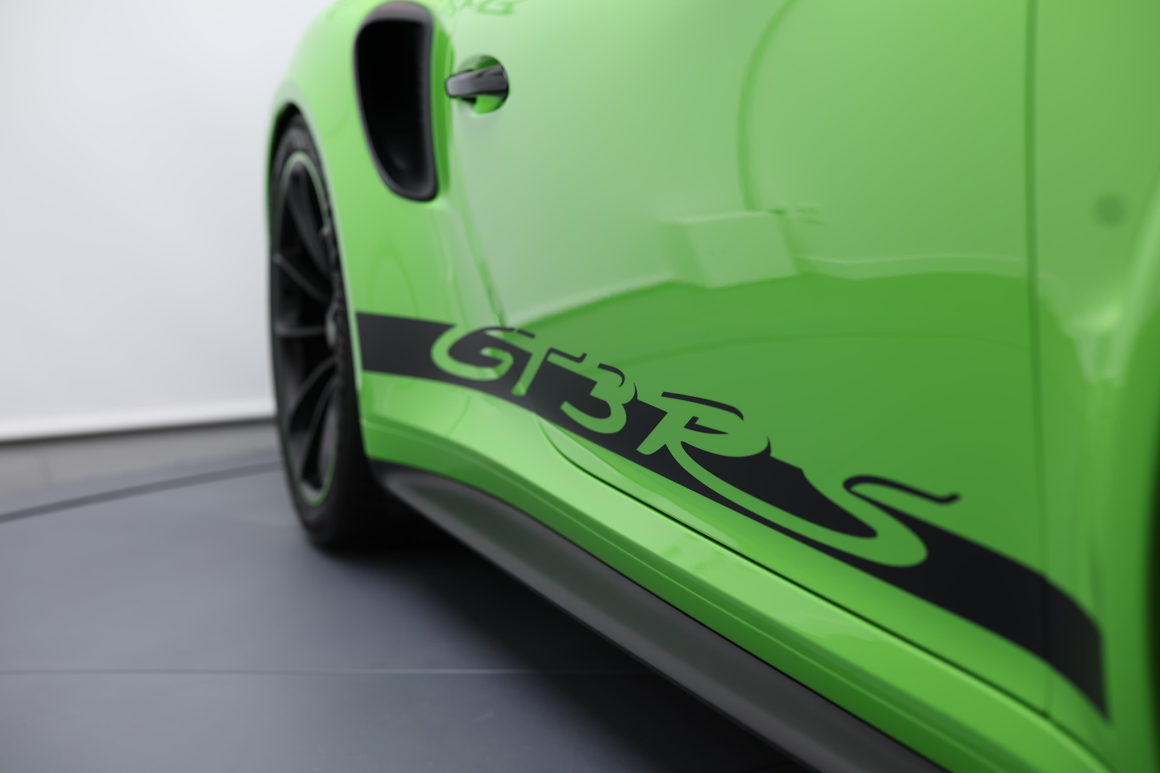 Détail du flanc arrière de la Porsche 911 GT3 RS 991 verte mettant en valeur le marquage « GT3 RS » et les prises d’air latérales, affirmant son ADN 100 % circuit.