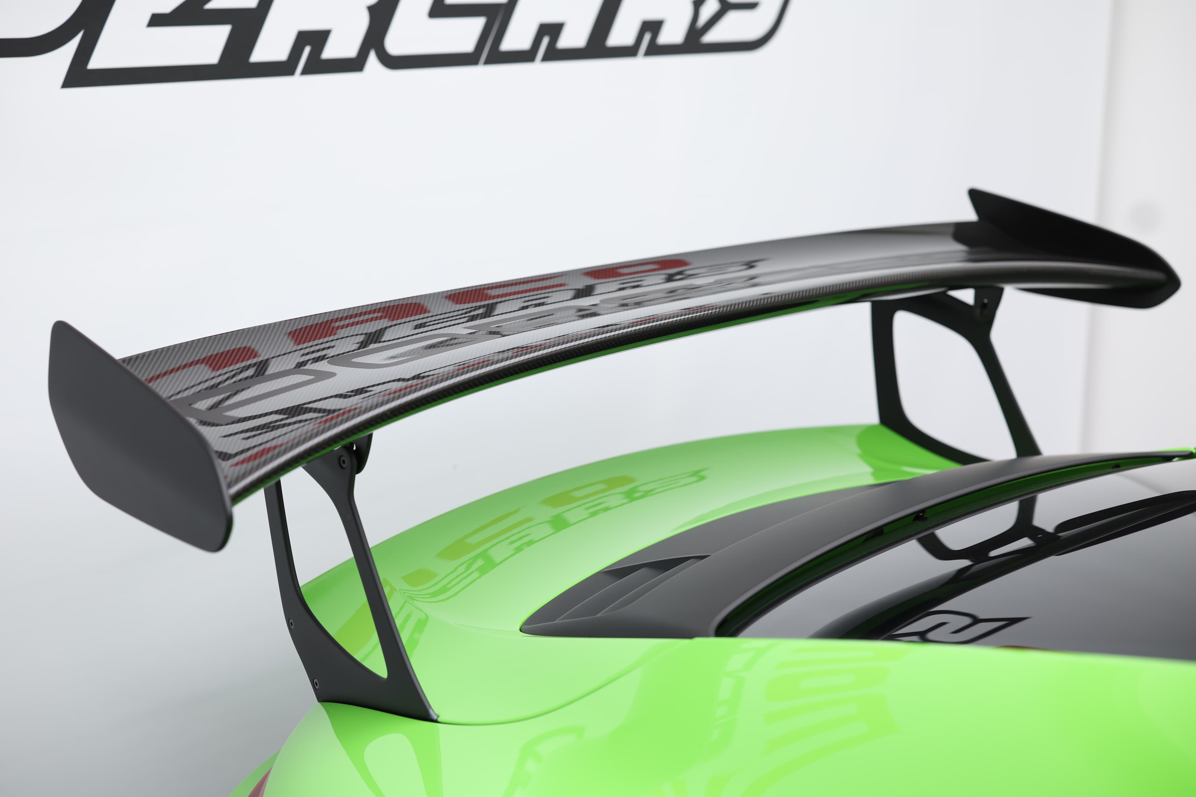 Détail de l’aileron arrière en carbone de la Porsche 911 GT3 RS 991 verte, élément aérodynamique emblématique assurant un appui maximal pour une performance optimale sur circuit.