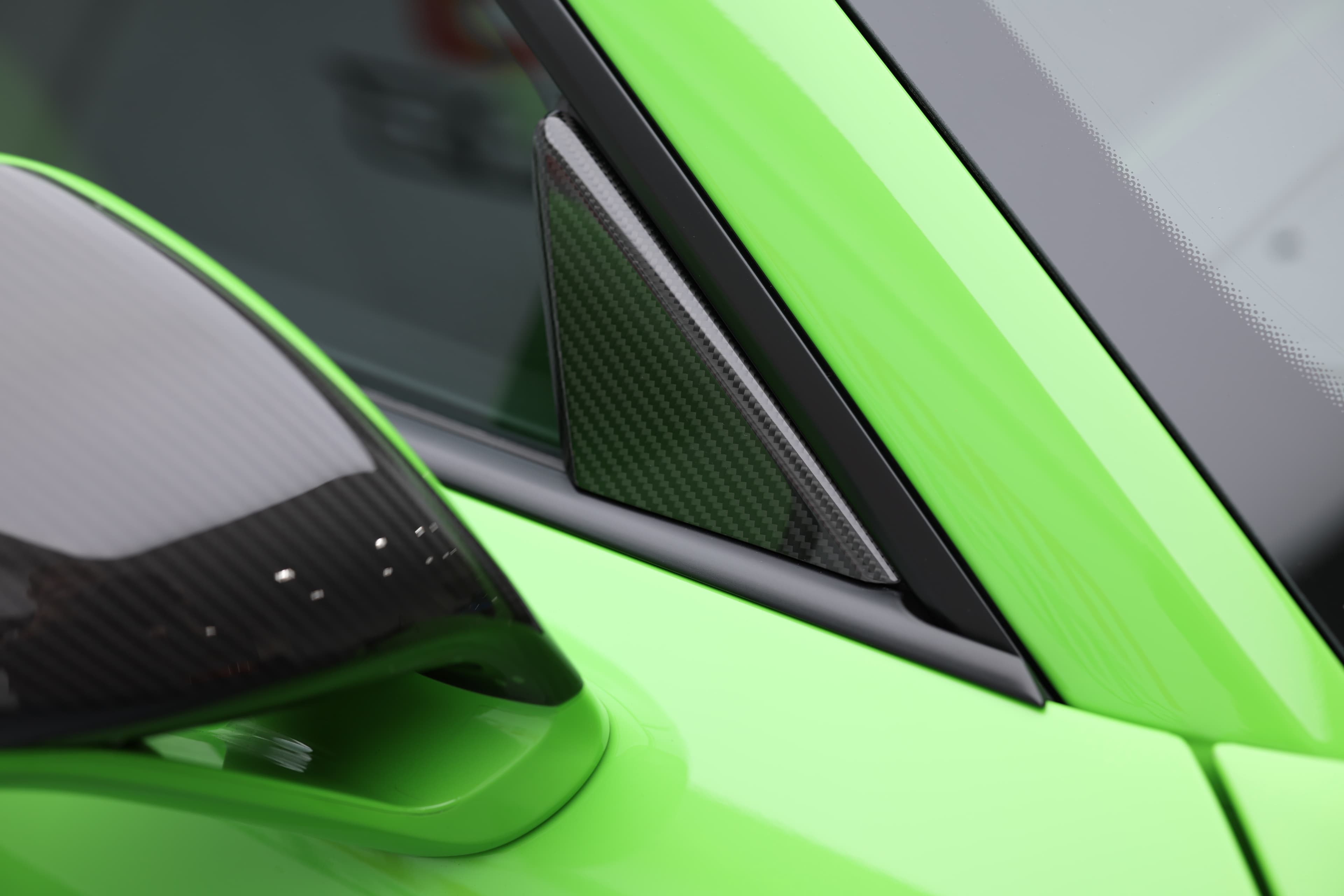 Détail du montant de porte et du rétroviseur en carbone de la Porsche 911 GT3 RS 991 verte, illustrant l’utilisation de matériaux légers et son design axé performance.