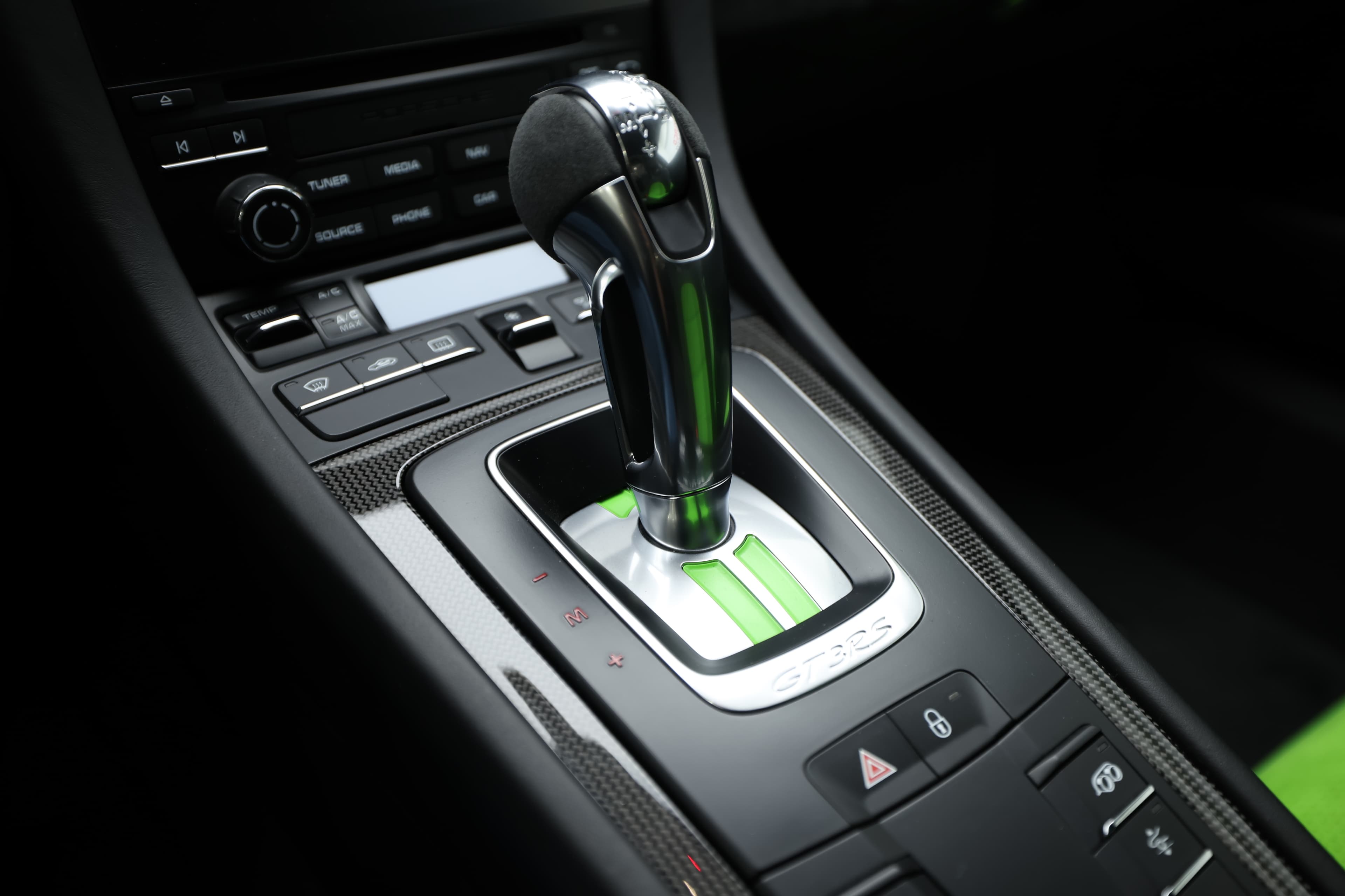 Le levier de vitesses de la Porsche GT3 RS se distingue par son design sportif et ergonomique. Le mélange de matériaux haut de gamme, associé à des touches de vert, accentue l’attrait de l’habitacle, tout en permettant une manipulation précise lors des changements de vitesses.