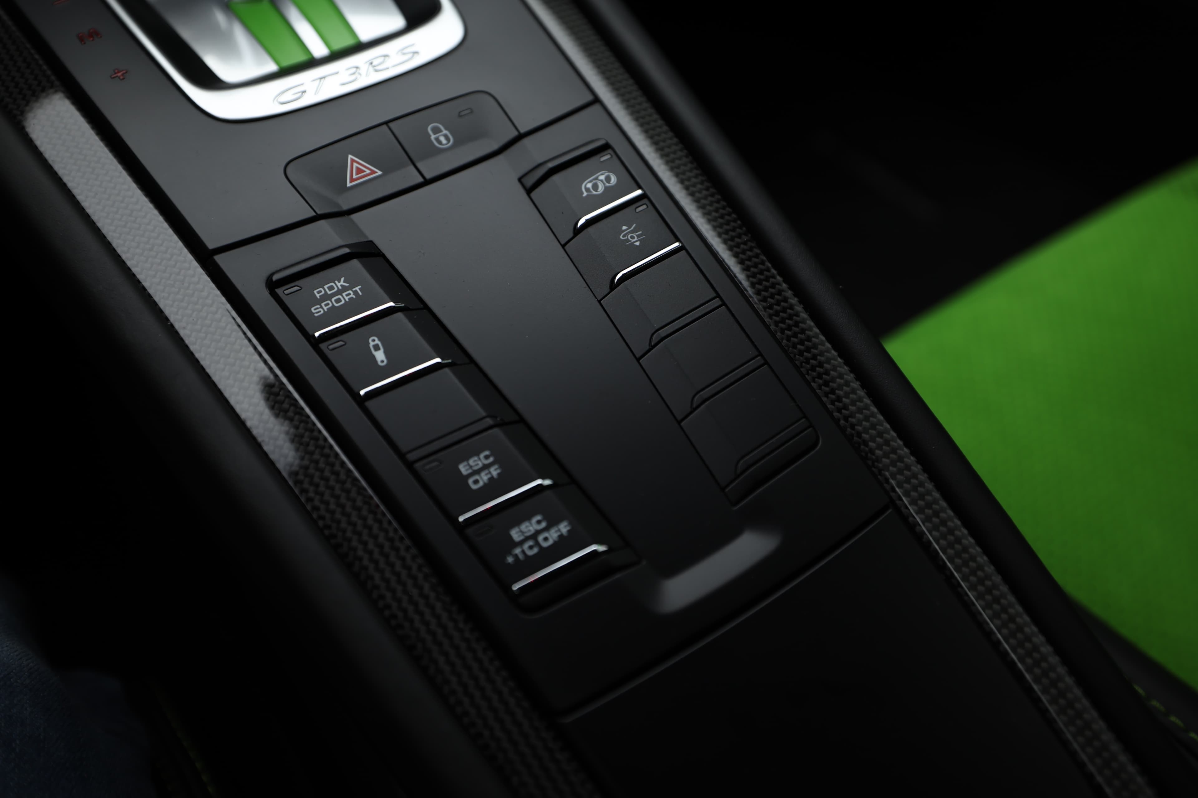 Les commandes situées sur le tunnel central de la Porsche GT3 RS sont conçues pour un accès facile et rapide. Ces boutons permettent de contrôler divers systèmes, de la climatisation à la gestion des performances, tout en intégrant des matériaux de haute qualité pour une sensation premium.