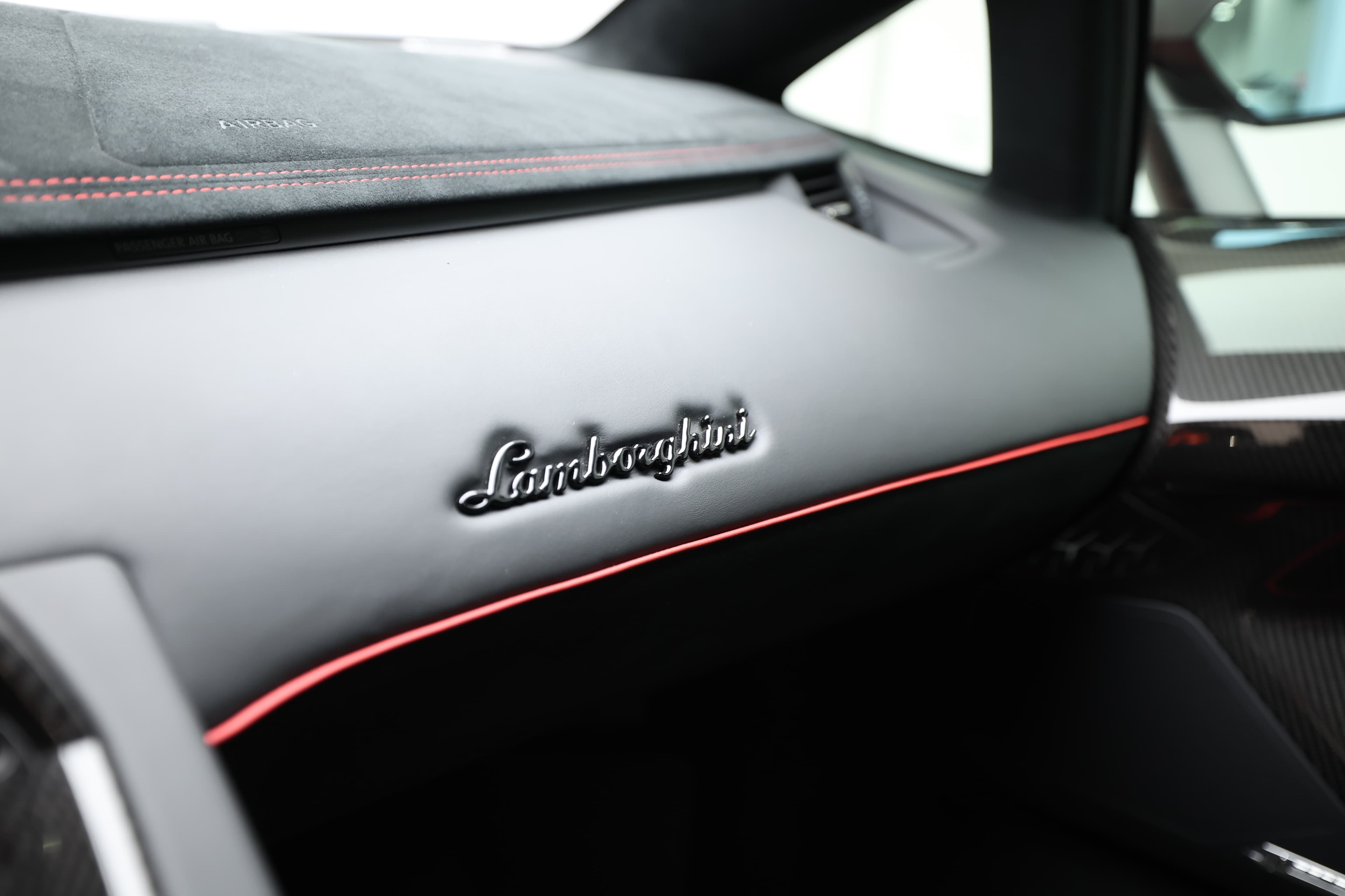 Vue panoramique du tableau de bord de la Lamborghini Aventador SV, recouvert d'une finition en alcantara. Cela renforce non seulement le luxe de l'intérieur, mais contribue également à une ambiance sportive, tout en mettant en valeur le savoir-faire artisanal de Lamborghini.