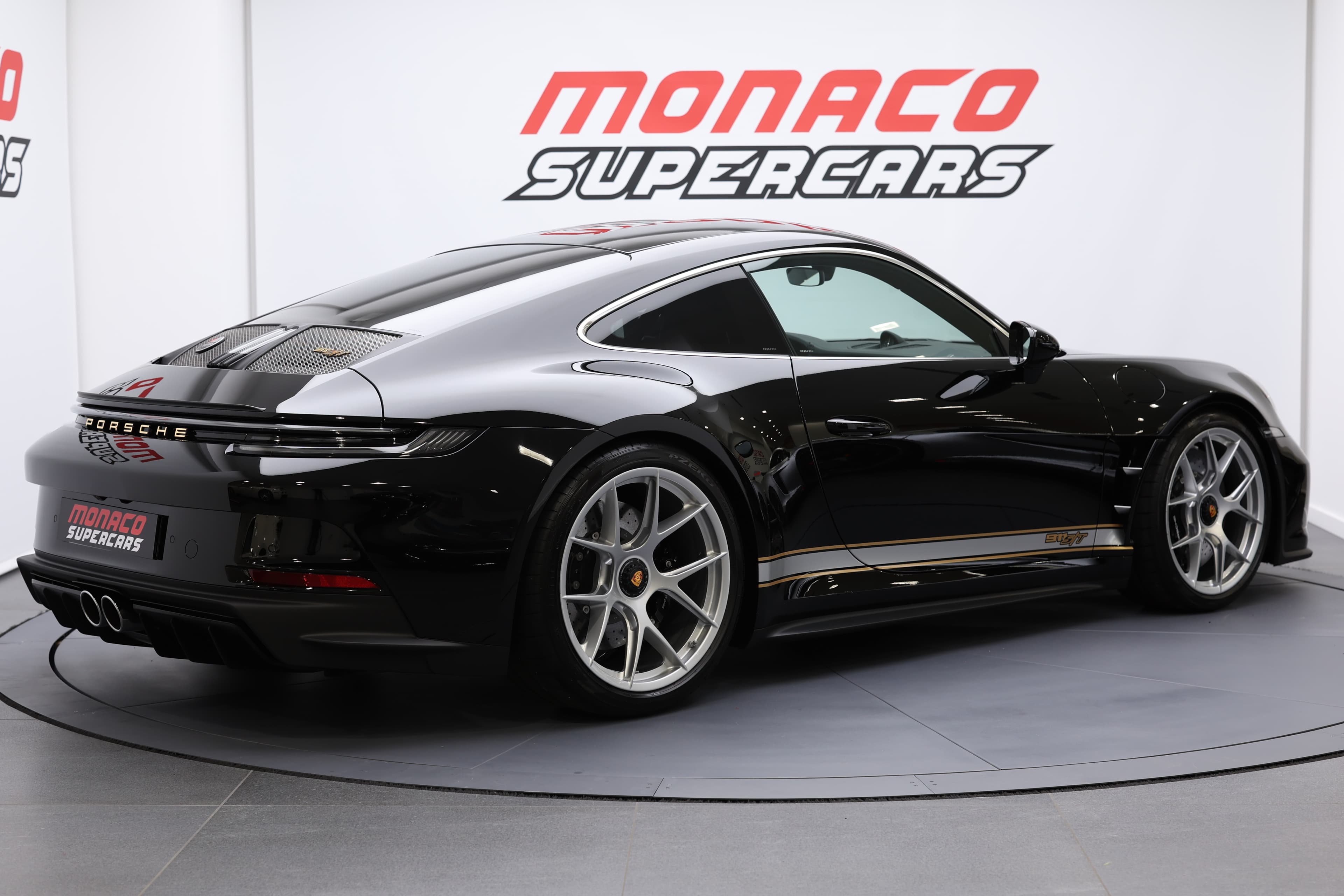 Porsche 911 en noir, vue trois-quarts arrière, mettant en avant ses lignes fluides et son allure sportive, présentée à Monaco Supercars, incarnant le luxe et la performance.