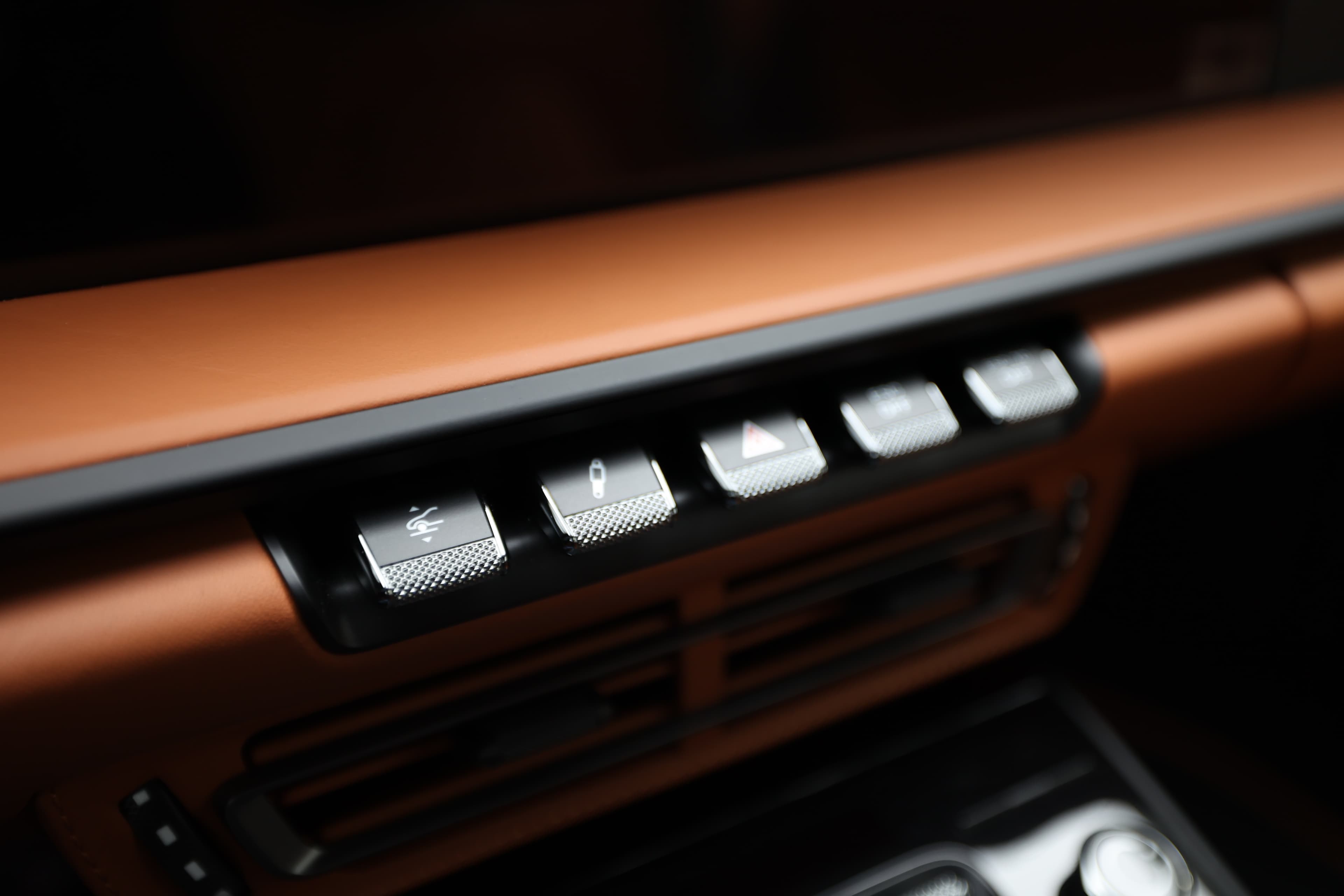Détail des commandes de la Porsche 911. Les boutons sont élégants et rétroéclairés, intégrés harmonieusement dans le design du tableau de bord. Le tout reflète un mélange de luxe et de fonctionnalité.
