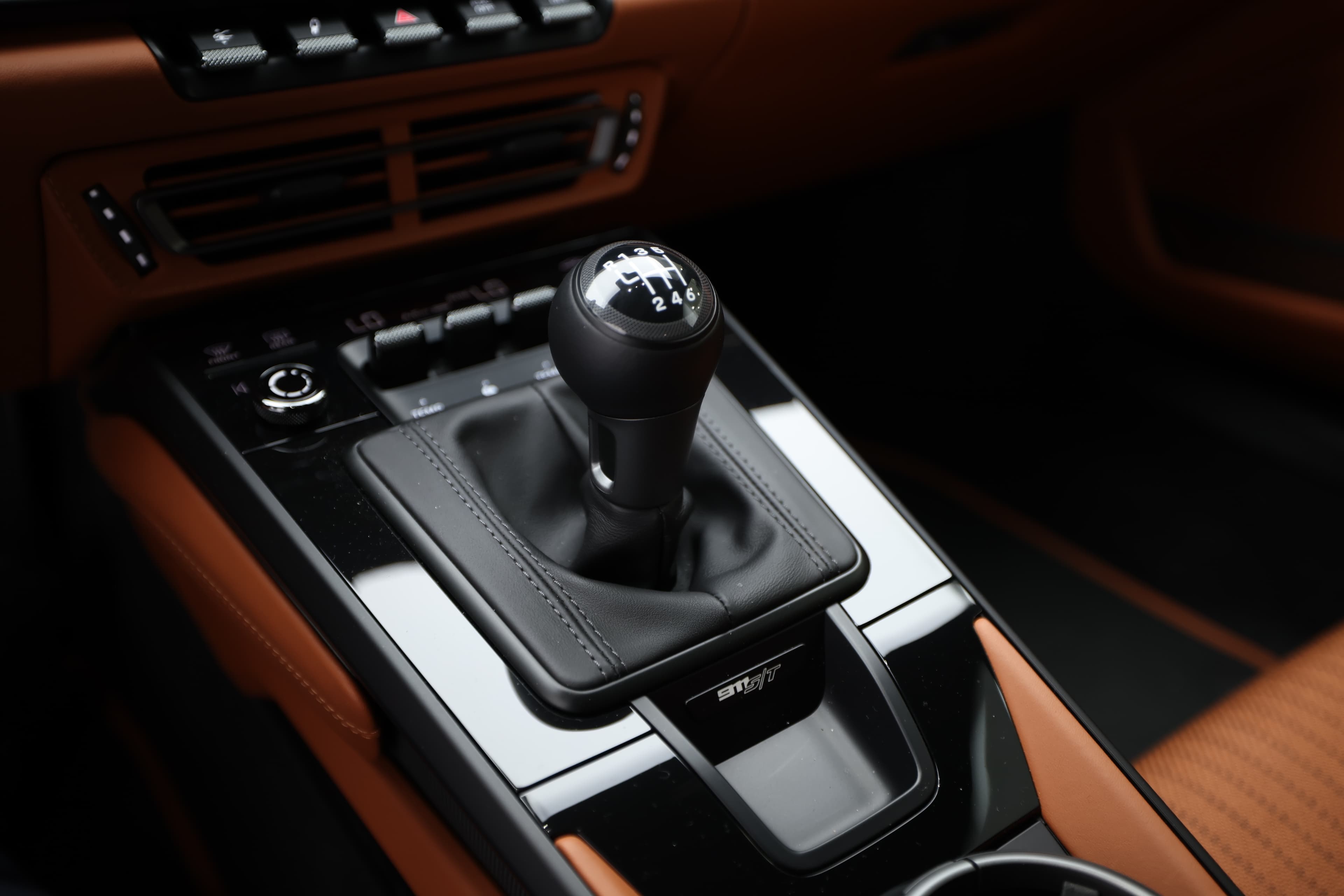 Autre vue du levier de vitesses de la Porsche 911. Le design est raffiné, avec des détails en métal et une finition soignée. Cette prise en main assure une expérience de conduite sportive et agréable, tout en complétant l'esthétique intérieure.