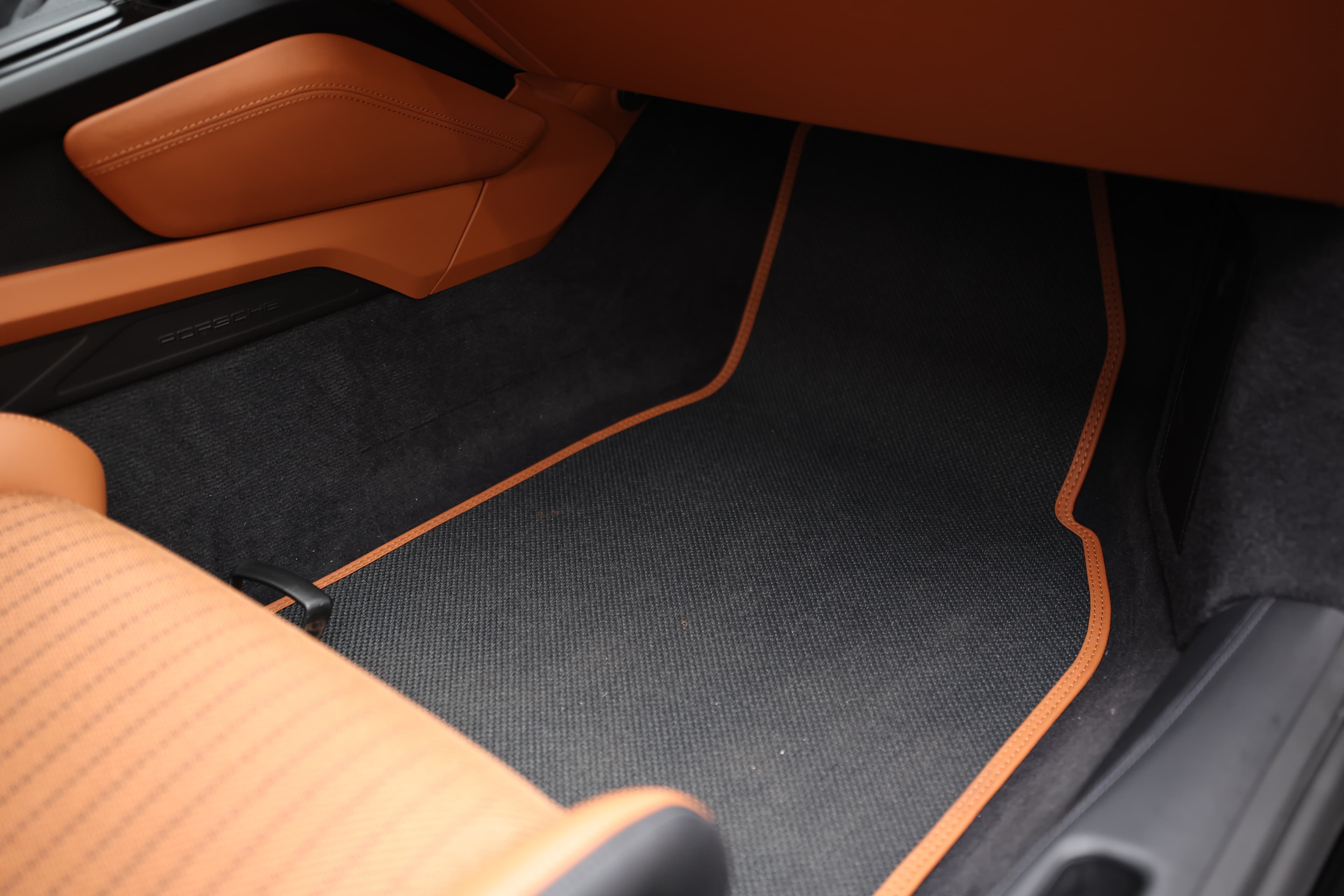 Un revêtement de sol élégant avec des bordures orange, complétant le design intérieur sportif et contemporain, garantissant à la fois style et confort dans cet habitacle haut de gamme.