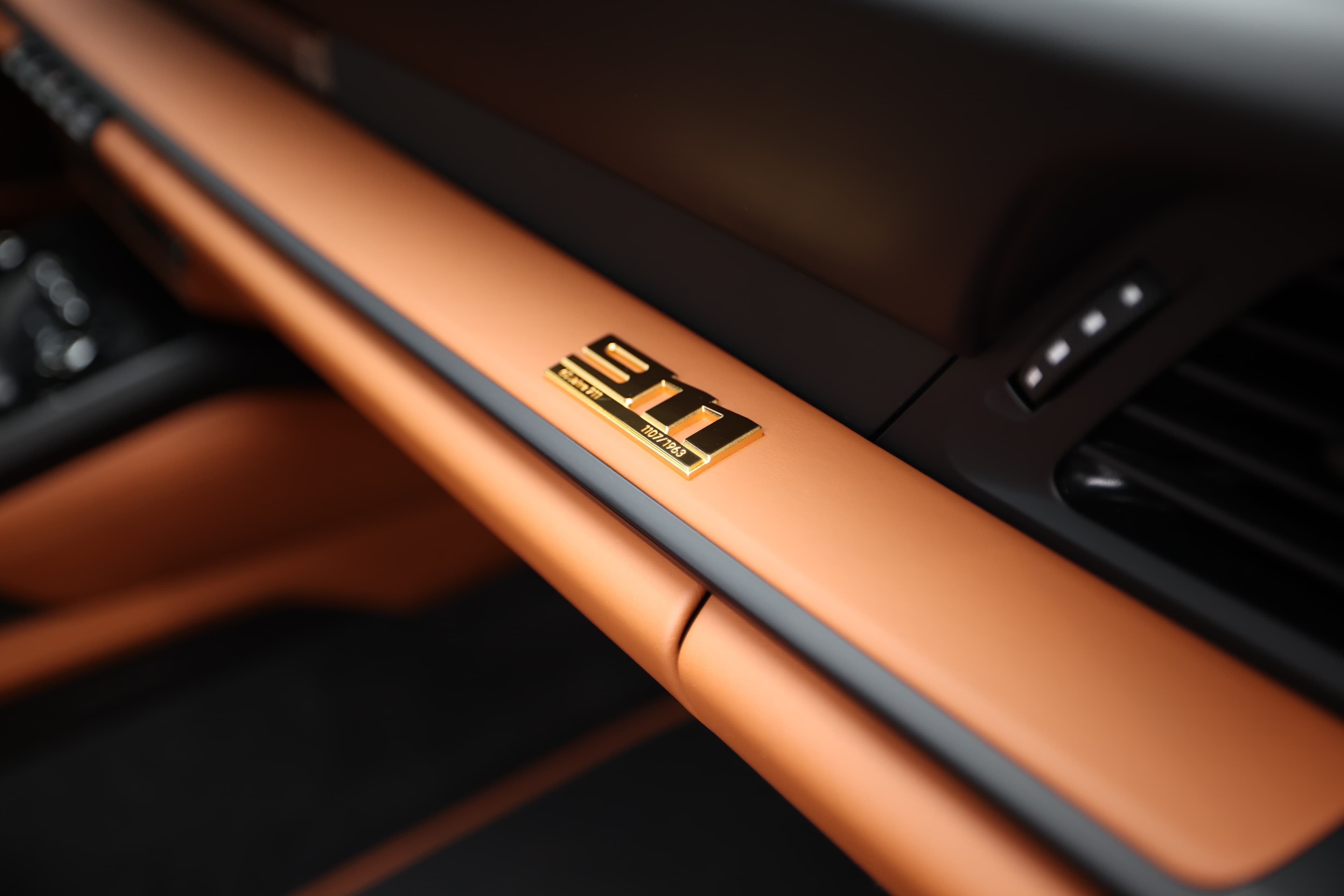 Un tableau de bord stylisé avec un accent orange vif et un logo distinctif, soulignant le design moderne et sportif, tout en offrant une touche d'élégance et de sophistication à l'intérieur du véhicule.